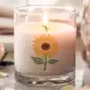 A Lit Candle In A Clear Glass Jar Decorated With A Sunflower.