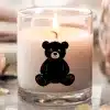 A Lit Candle With A Black Teddy Bear Silhouette On Its Side.