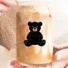 A Person Holds A Glass Iced Coffee With A Black Teddy Bear Design.
