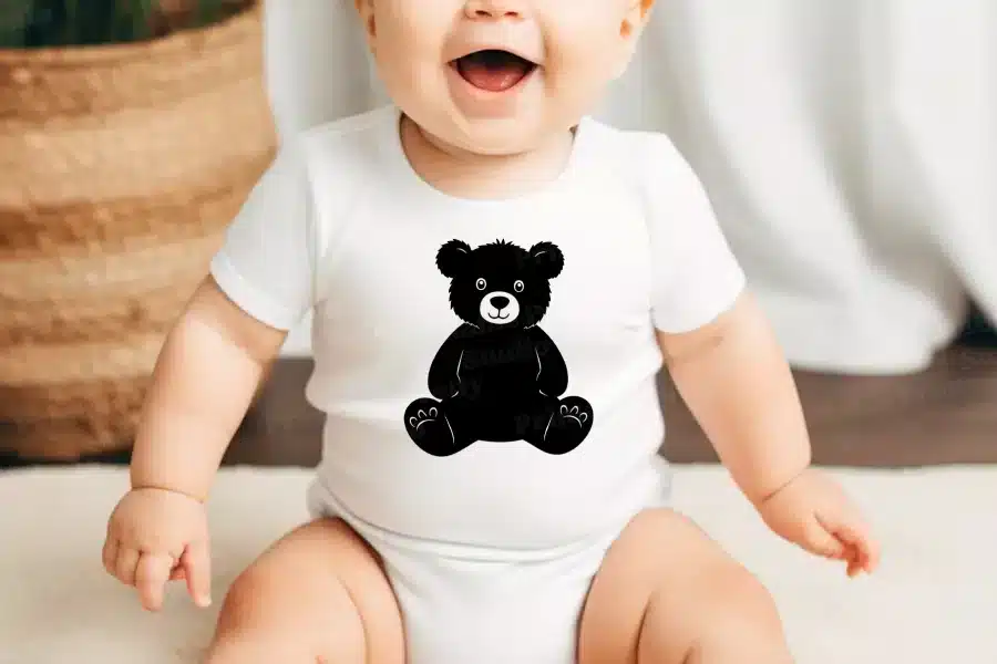 Baby wearing a white onesie with a black teddy bear design.