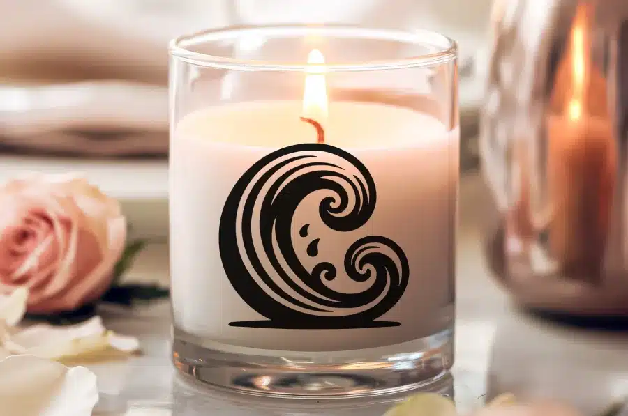A Lit Candle In A Clear Glass Jar With A Black Wave Design.