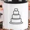 White Coffee Mug With A Black Handle, Featuring A Line Drawing Of A Three-Tiered Wedding Cake Topped With A Heart.
