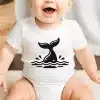 Baby Wearing A White Onesie With A Black Whale Tail Design.