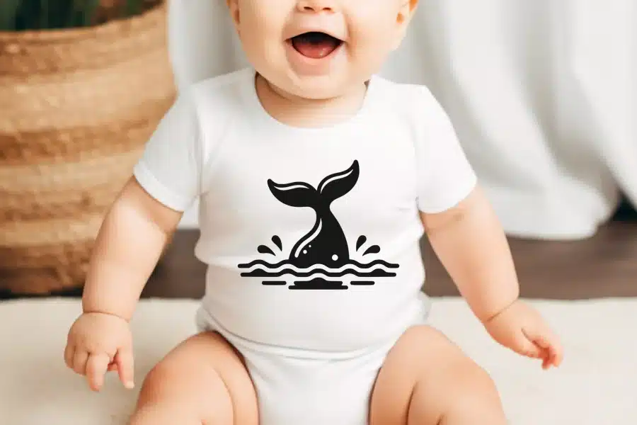 Baby wearing a white onesie with a black whale tail design.