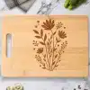 Light Brown Bamboo Cutting Board With A Dark Brown Floral Design.