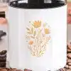 White Coffee Mug With A Black Handle, Featuring A Mustard Yellow Floral Design.