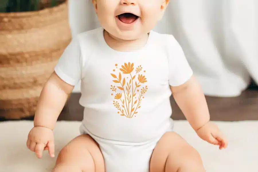 Baby Wearing A White Onesie With An Orange Floral Design.