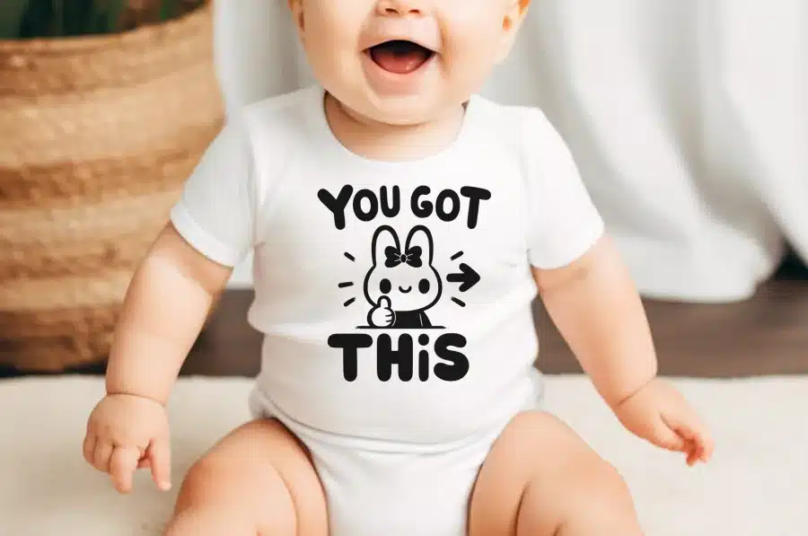 Baby Wearing A White Bodysuit With A Bunny Graphic And The Text You Got This.